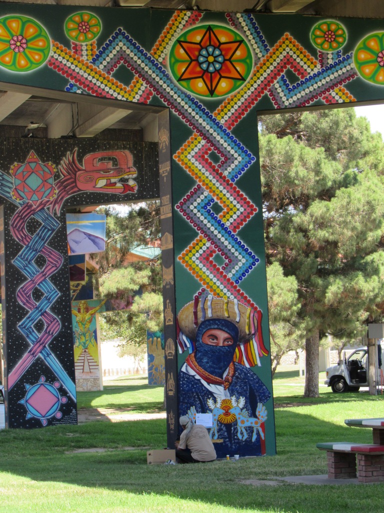 A man sitting on the lawn working on a mural at a park